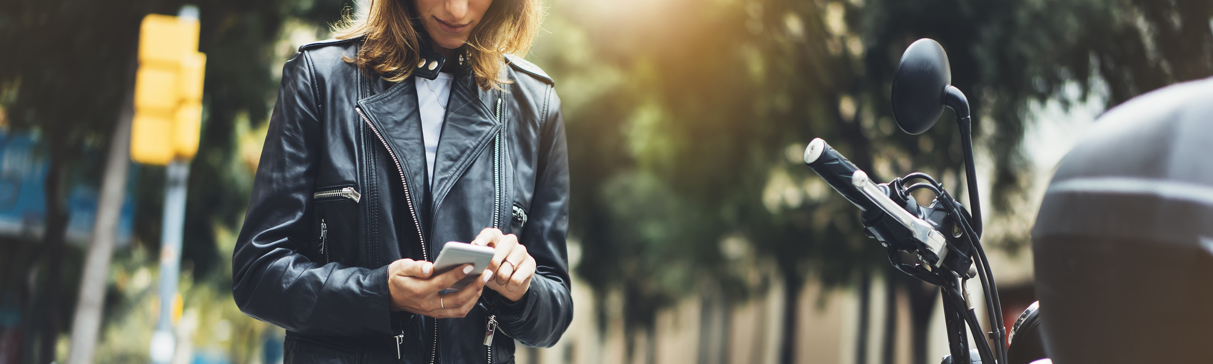 Female motorcycle rider on her phone by her bike.